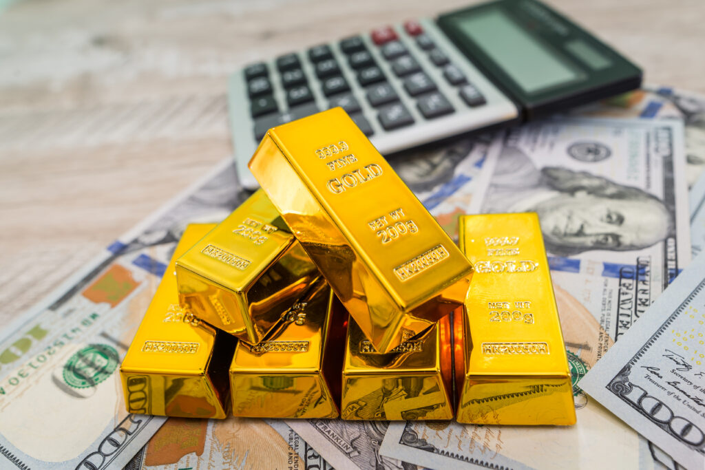 Gold bars with calculator and dollars.