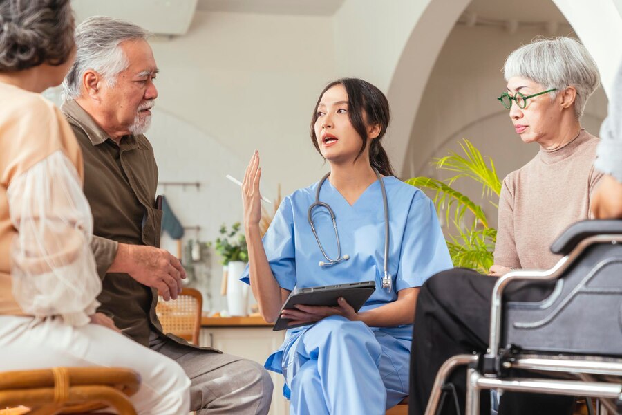 Happiness cheerful elderly woman men talking with female caregiver nurse doctor having health checking consult living areacaretakers with senior couple sitting living room nursing home 609648 3092