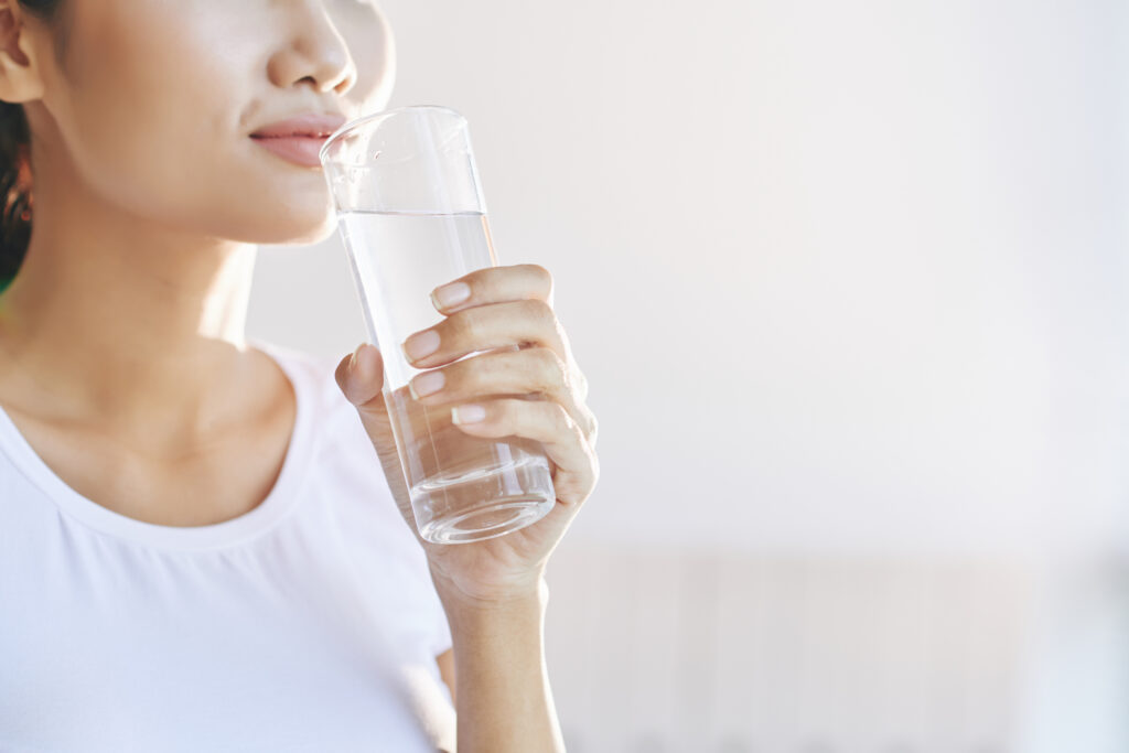 Unrecognizable woman carrying glass water mouth