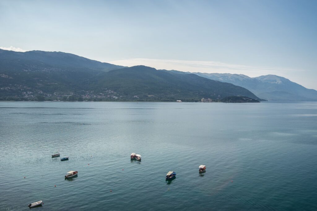 Sea with boats it surrounded by hills covered greenery sunlight