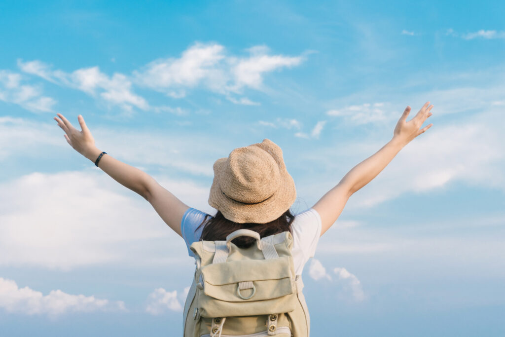 Woman traveler with backpack holding hat looking blue sky travel concept space text atmospheric moment