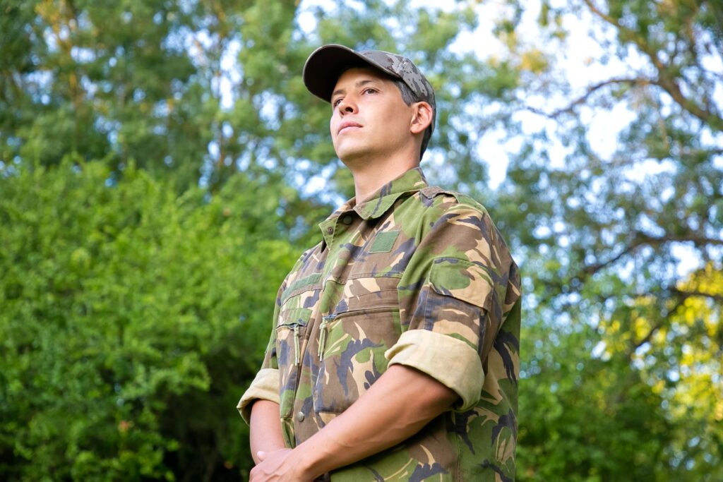 Serious man military camouflage uniform standing park looking away