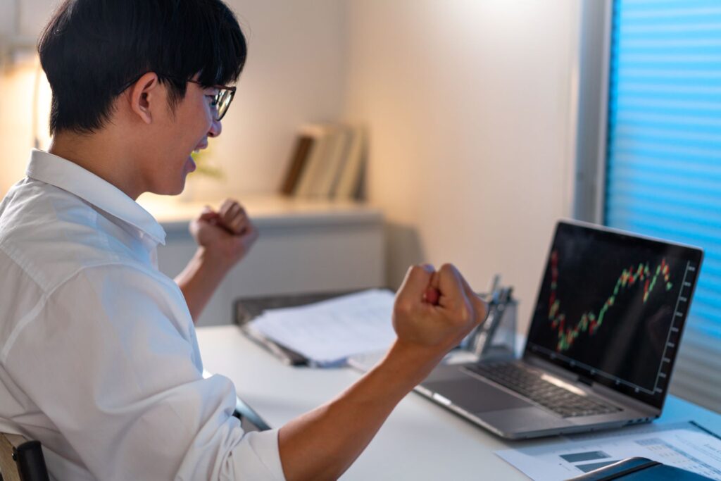 Overwork concept man sitting desk office raising his hand with happy emotion