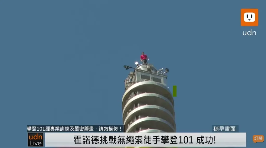 艾力克斯.霍諾德站在台北101高處,背景為晴朗藍天。