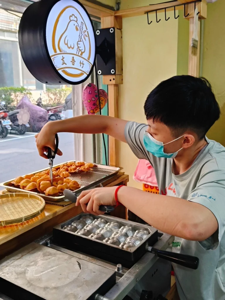 店主於攤位現場製作雞蛋糕,從烤模操作、翻烤到成品整理,皆希望維持穩定口感與品質。/圖片來源 : 支吾竹雞蛋糕